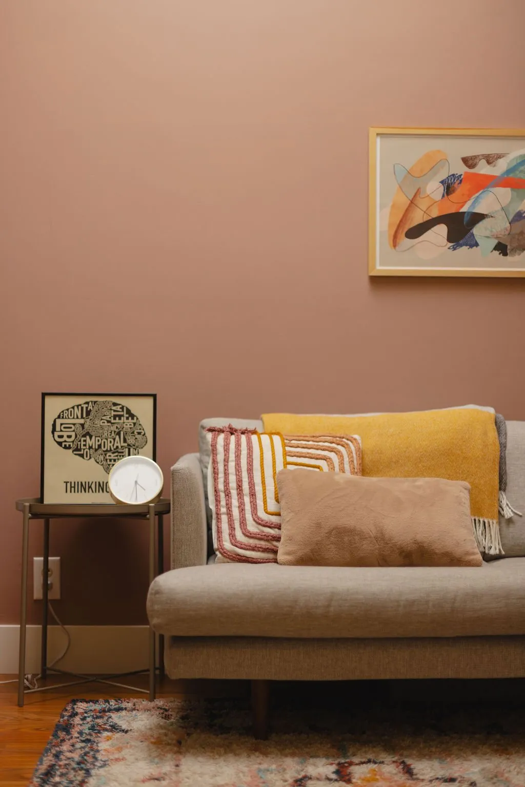 A warm, light-filled therapy office with a sofa, throw pillows, and a side table in Carlsbad, California.