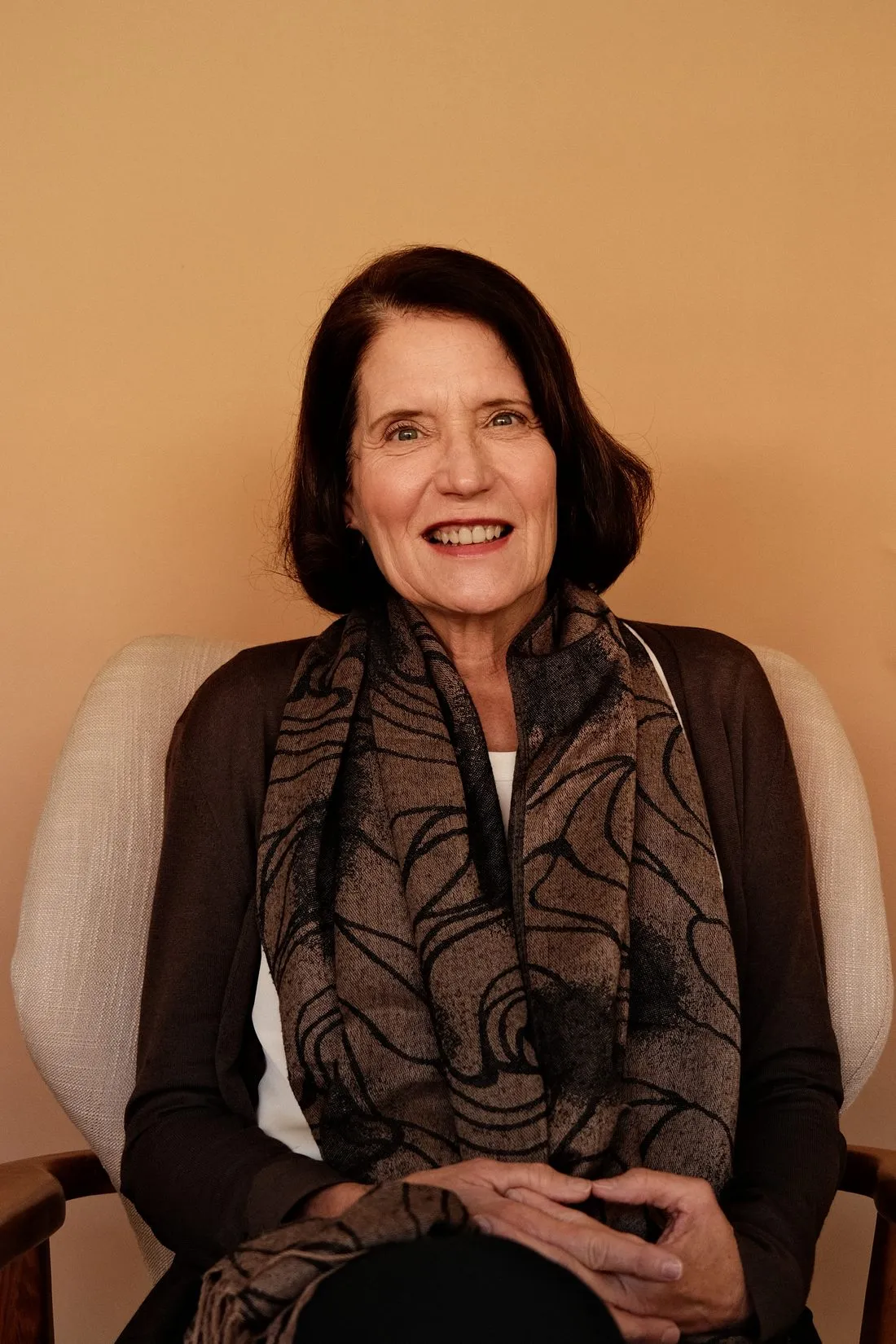 Kari, the warm, smiling care coordinator at Coastal Therapy Group, seated in a chair.