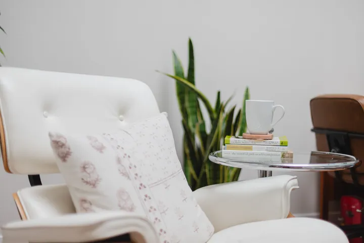 A quiet therapy office in Carlsbad with a reading chair, a warm mug, and a stack of self-compassion books