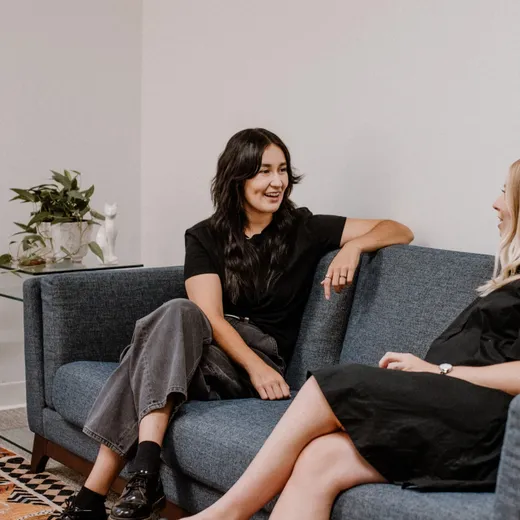 Two therapists in conversation on a couch at Coastal Therapy Group